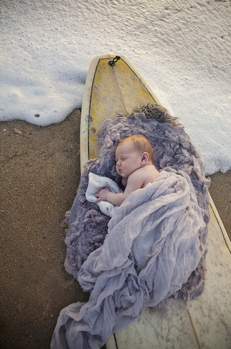 Newborn photo of newborn baby on surfboard in Outer Banks NC